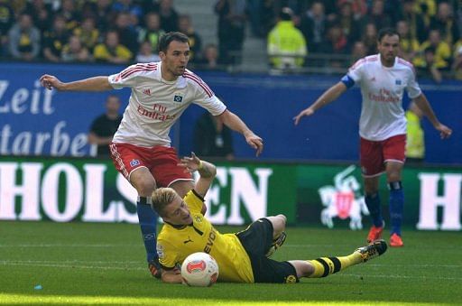 Hamburg's midfielder Milan Badelj (L) and Dortmund's striker Marco Reus (C) fight for the ball